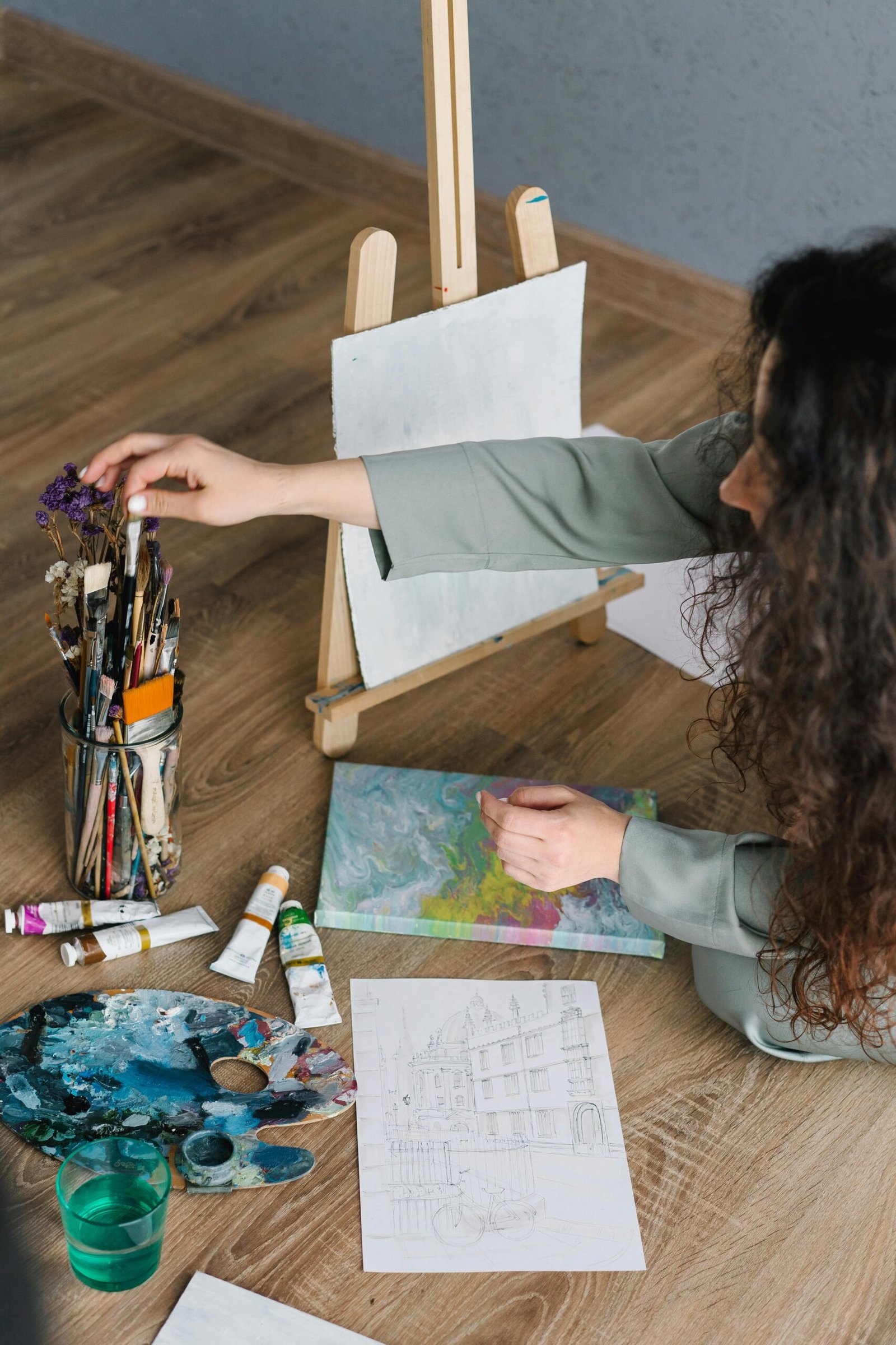 A woman artist working on a painting in a home studio with various art supplies.