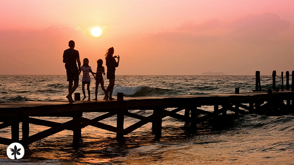 A family walking on a pier over the beach