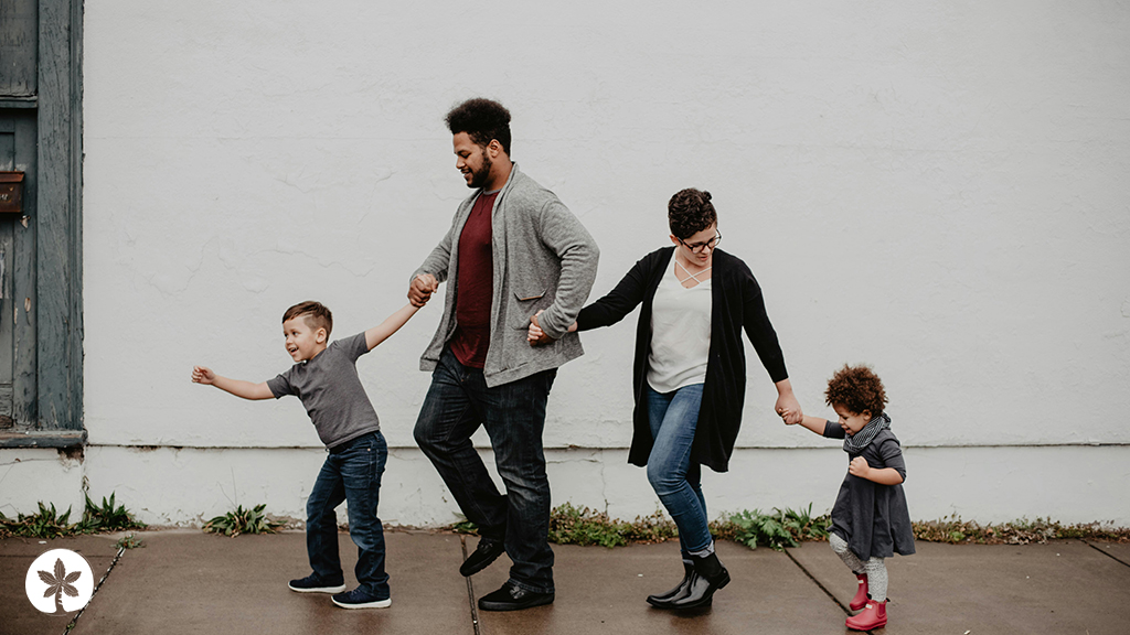 Family walking holding hands walking beside white building