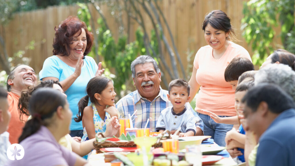 Joyful Latino family gathered having an outdoor meal with the father at the center